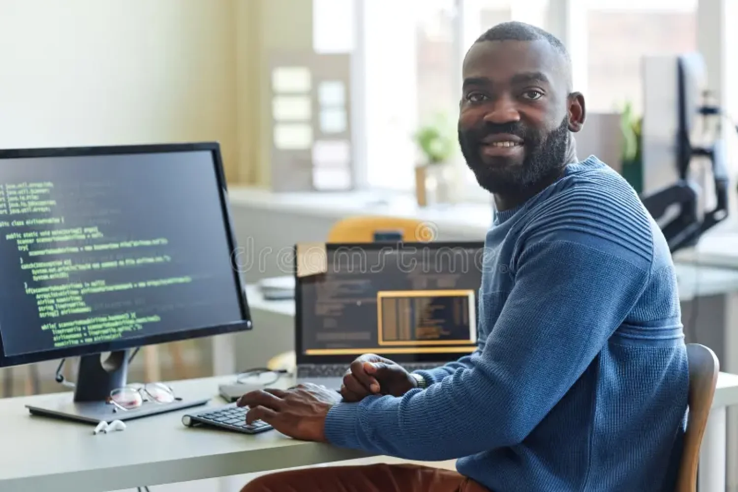 portrait-black-man-as-computer-programmer-looking-camera-writing-code-office-workplace-software-developer-smiling-259368462